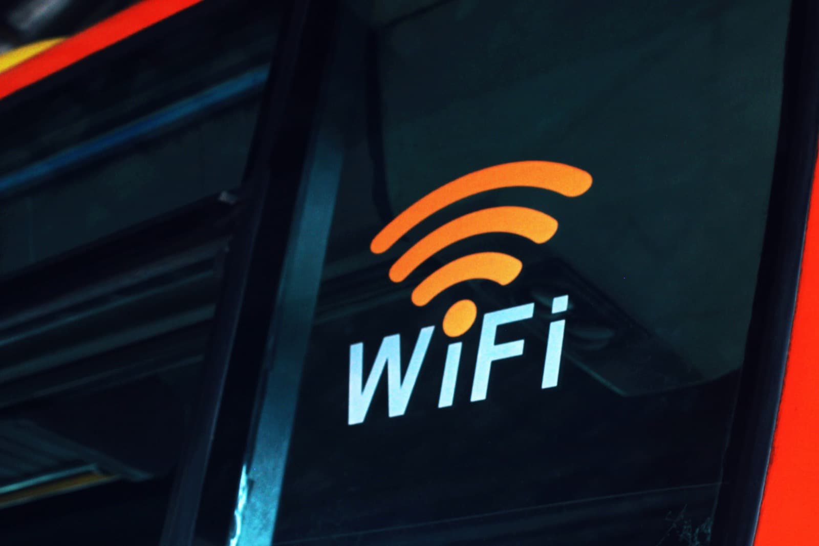 Oplyst wifi-symbol og teksten WiFi på en mørk glasrude